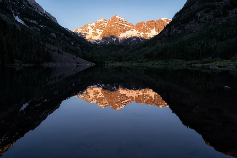 Maroon Bells peaks above Maroon Lake at sunrise near Aspen