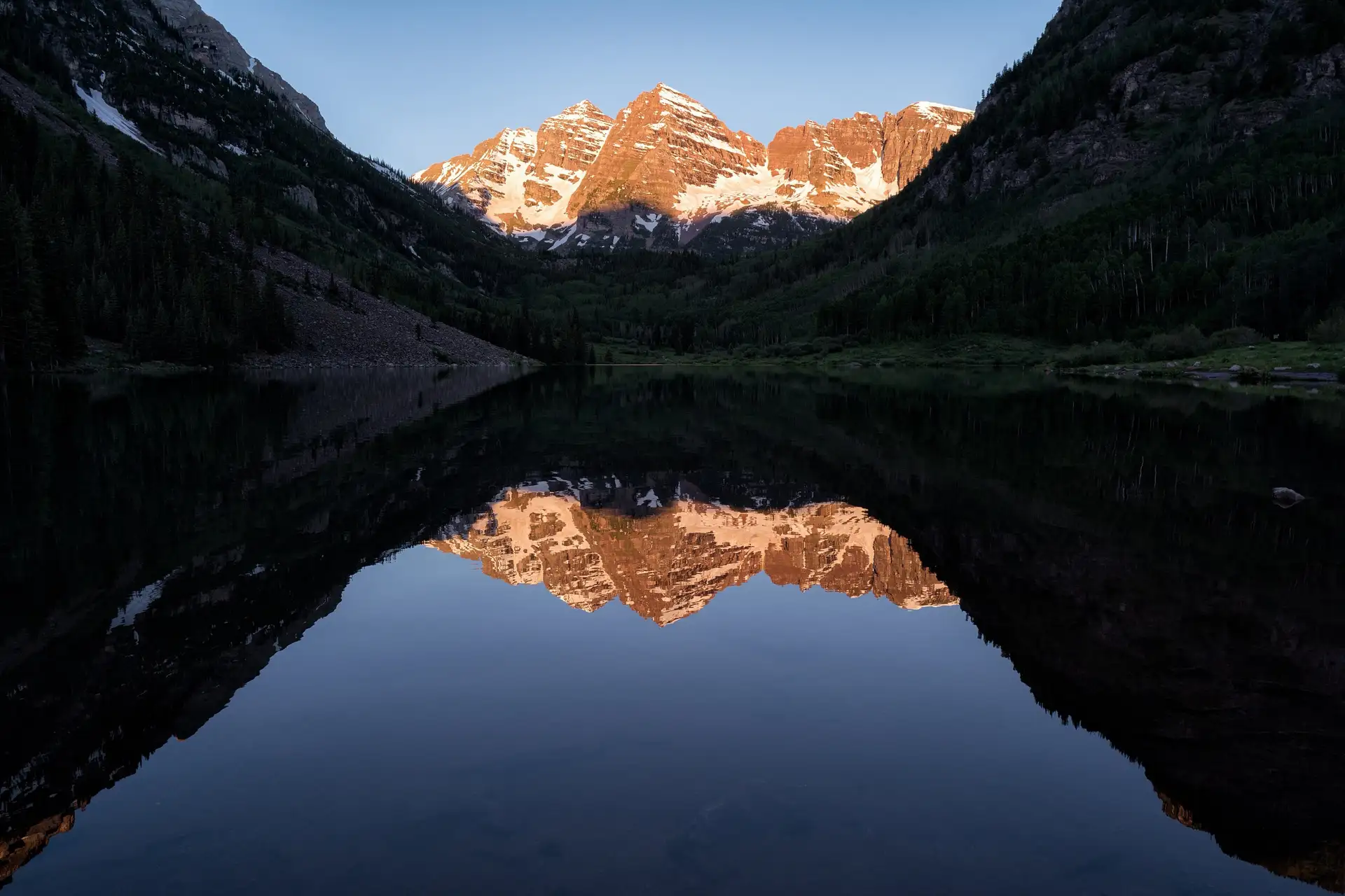 Maroon Bells peaks above Maroon Lake at sunrise near Aspen